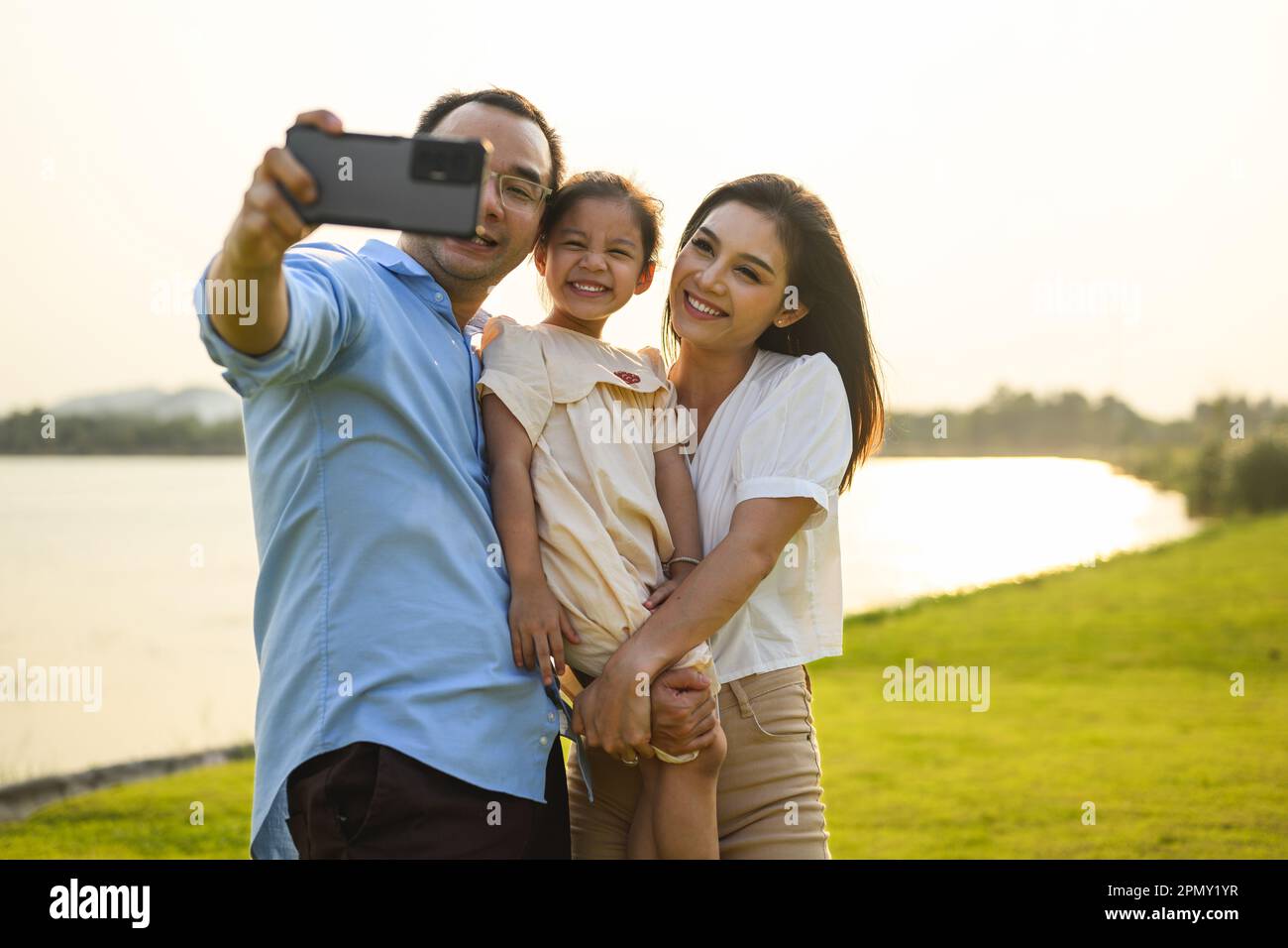 Familie macht Selfie-Fotos mit grüner Wiese und Blick auf den Fluss Stockfoto