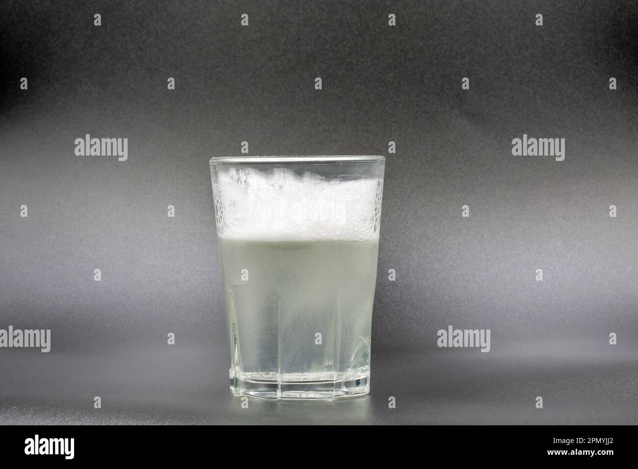 Auflösen von Brausetabletten in einem Glas mit Wassernaht auf Schwarz Stockfoto