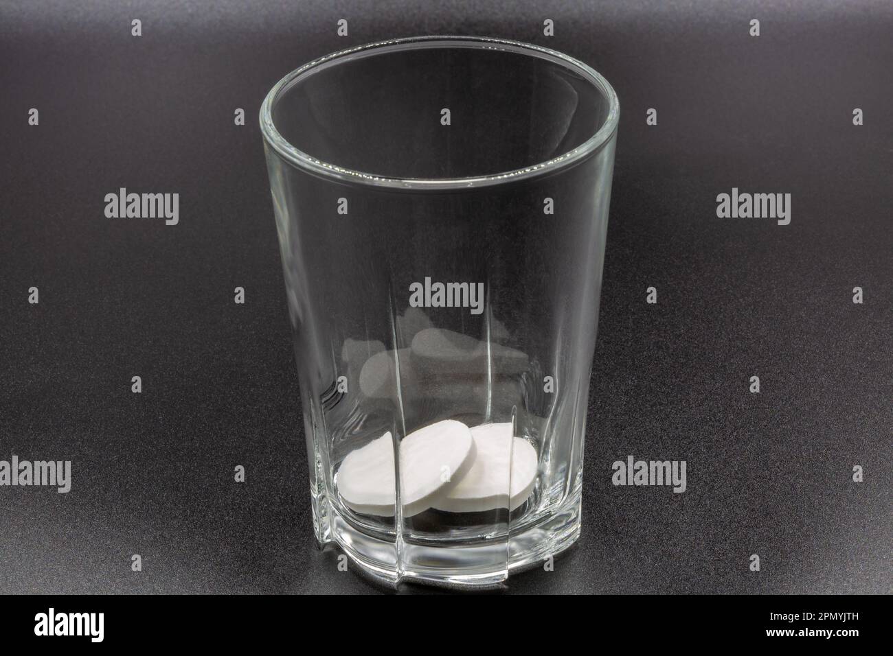 Auflösen von Brausetabletten in einer Glasnaht auf schwarzer Farbe. Bereit zur Auflösung und Zubereitung eines Getränks. Stockfoto