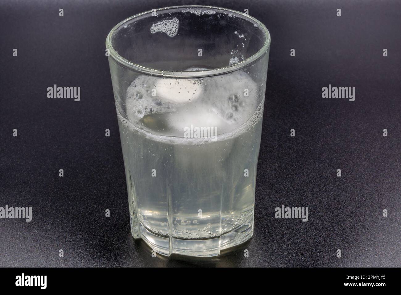 Auflösen von Brausetabletten in einem Glas mit Wassernaht auf Schwarz Stockfoto