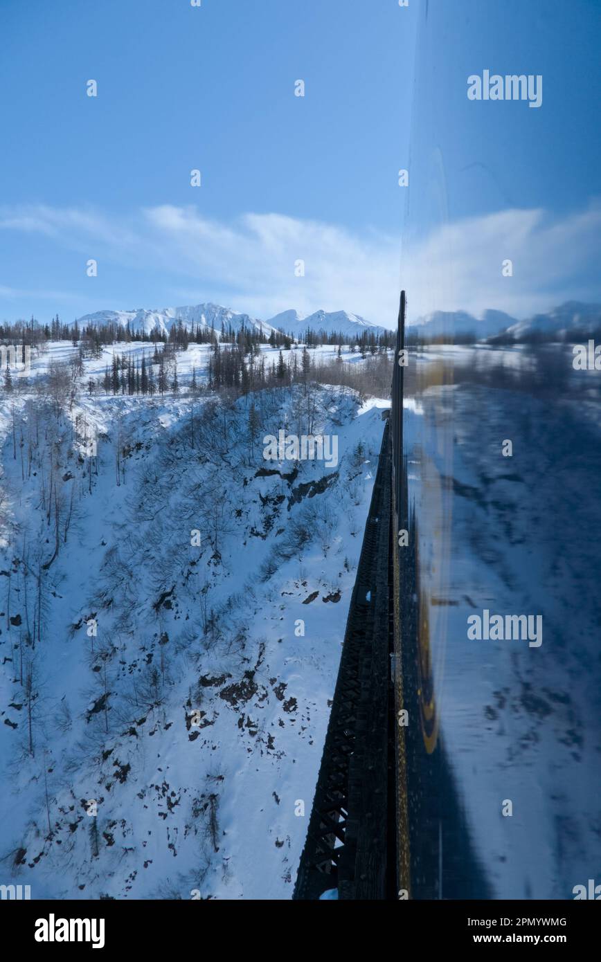 Gleis- und Zugreflektionen mit blauem Himmel und Schnee im Boden. Stockfoto