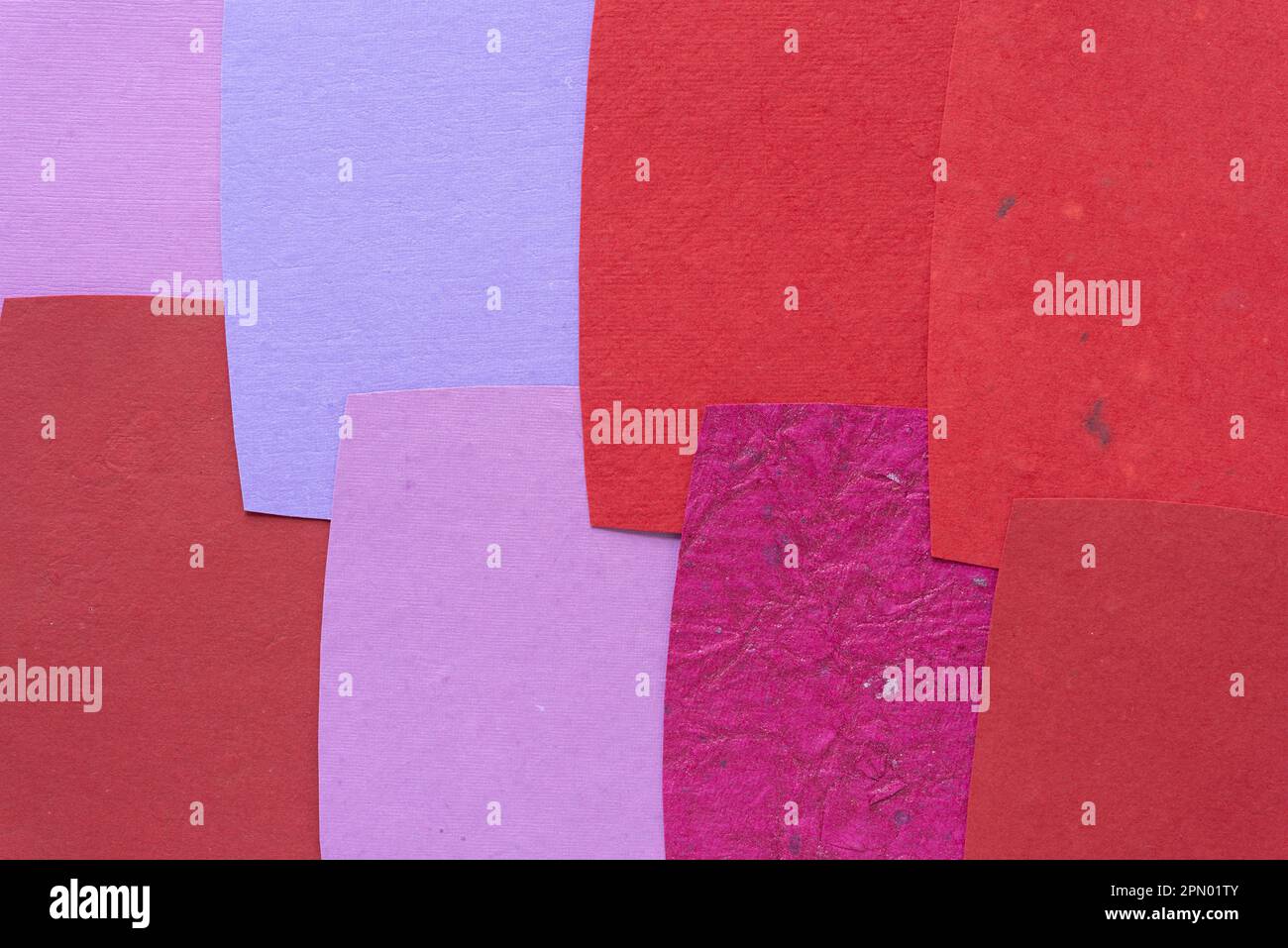 Papierhintergrund mit geschnittenen Papierbögen – einige mit eher rauer Textur – überlappend angeordnet – warme Farbpalette Stockfoto