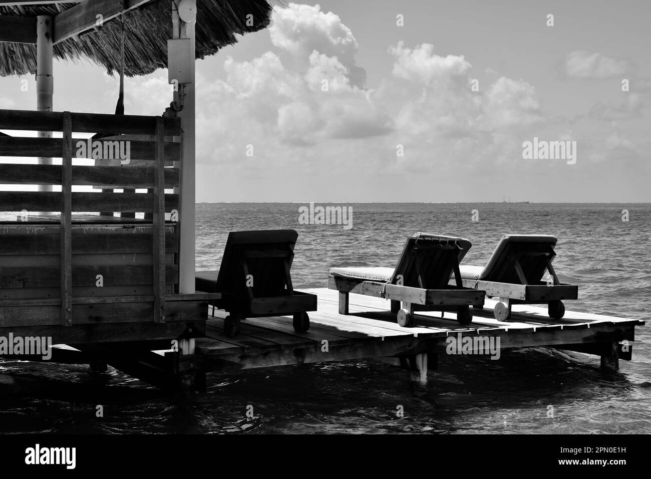 Liegestühle an einem Dock mit Blick auf das Meer an klaren Tagen in San Pedro, Ambergris Caye, Belize, Karibik/Mittelamerika. Stockfoto