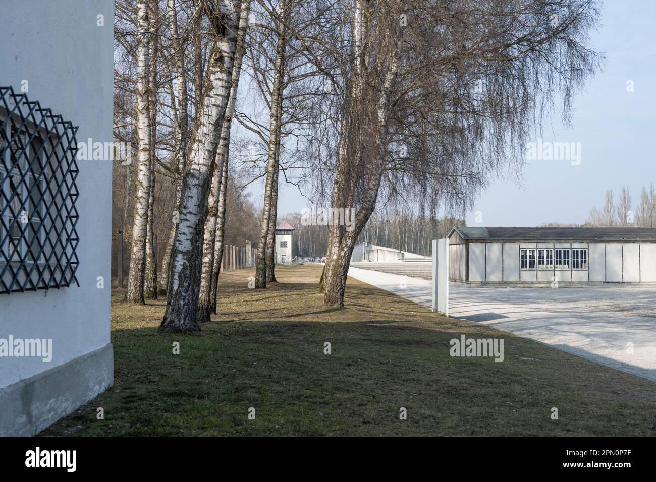 Blick nach dem Betreten des Dachau-Lagers mit einer rekonstruierten Baracke auf der rechten Seite und einem Wachturm in dieser Entfernung und der Lage der ehemaligen Baracken Stockfoto
