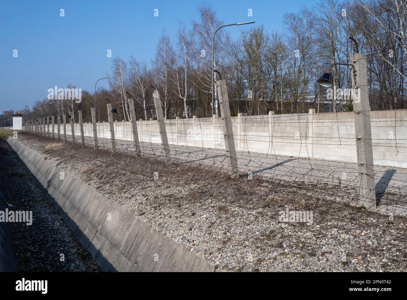 Graben und elektrischer Stacheldrahtzaun in der Nähe eines Wachturms, um Gefangene vor der Flucht im Konzentrationslager Dachau zu bewahren Stockfoto