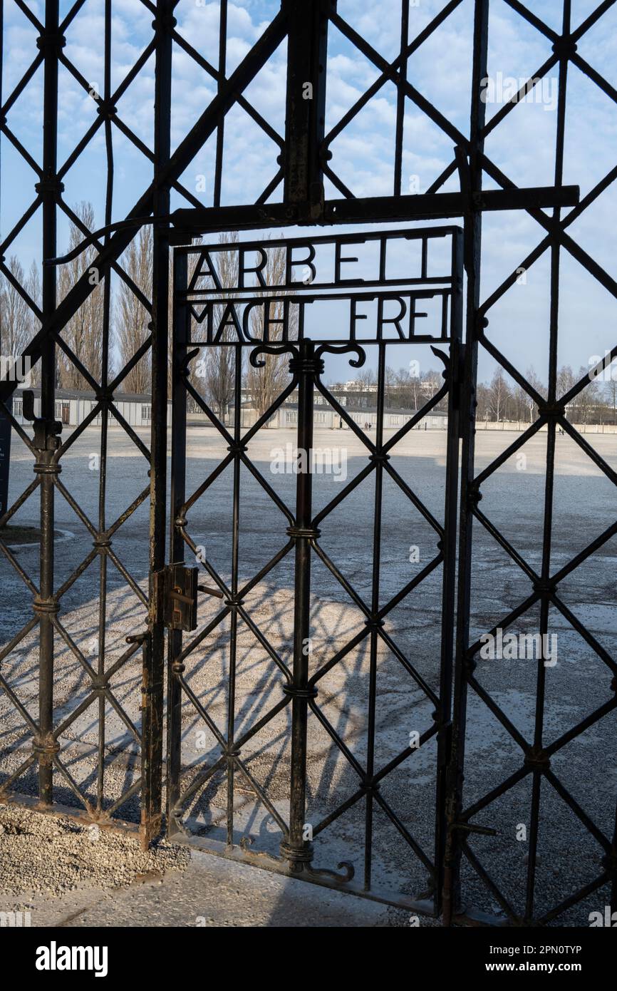 Die Gefangenen des Eingangstors kamen vorbei und sagten, dass die Arbeit einen frei macht mit Blick auf die Baracken im Hintergrund Stockfoto