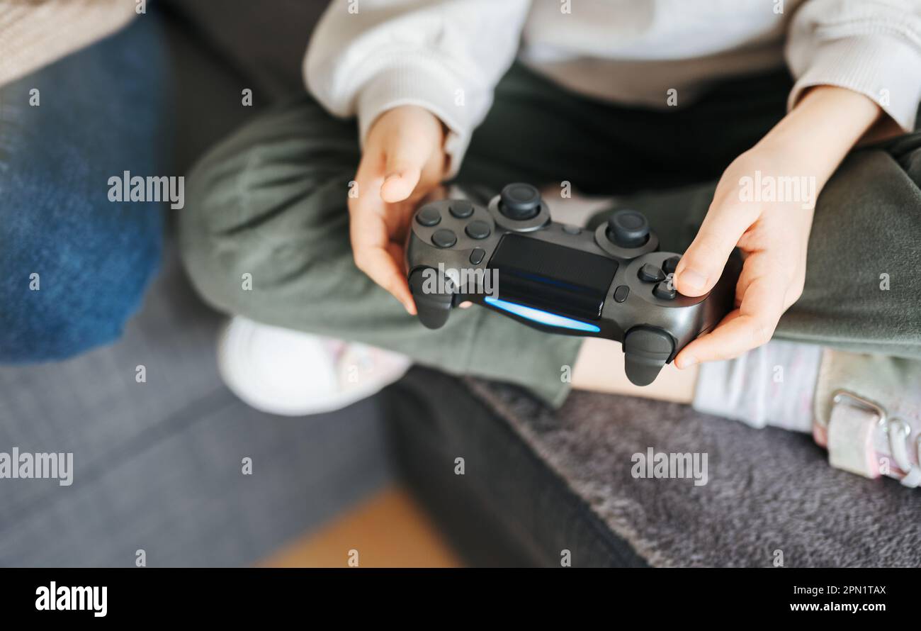 Ein kleines Mädchen, das den Gamecontroller hält und Videospiele spielt Stockfoto