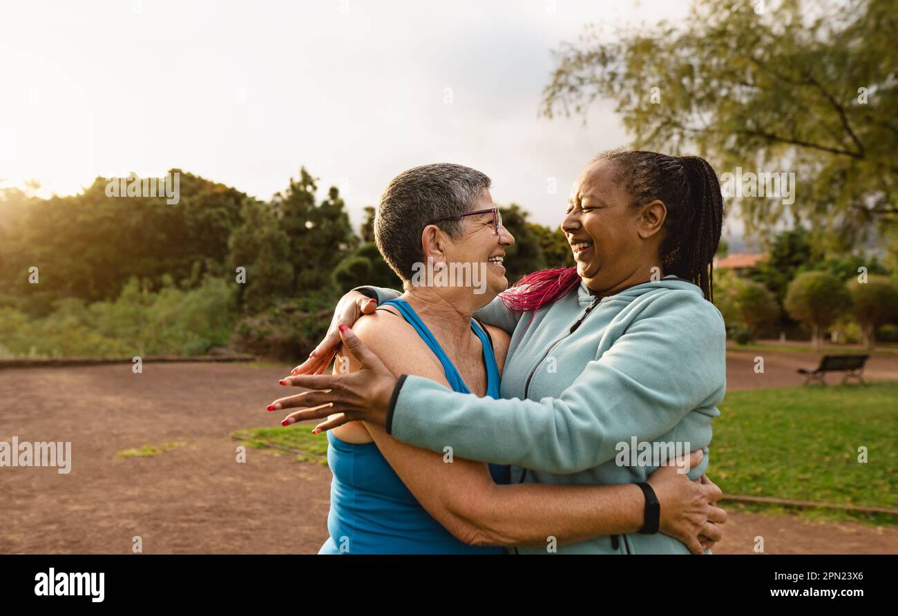 Glückliche, multiethnische Seniorinnen, die nach dem Training in einem öffentlichen Park Spaß haben - Konzept für gesunde ältere Menschen Stockfoto