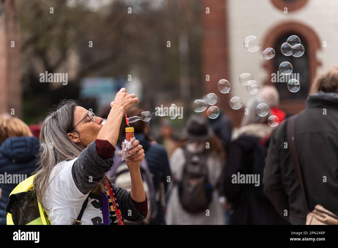 Weibliche Protestantin bläst Seifenblasen während der Friedensveranstaltung auf Kaiserslautern. 8. April 2023, Schillerplatz, Kaiserslautern, Deutschland Stockfoto