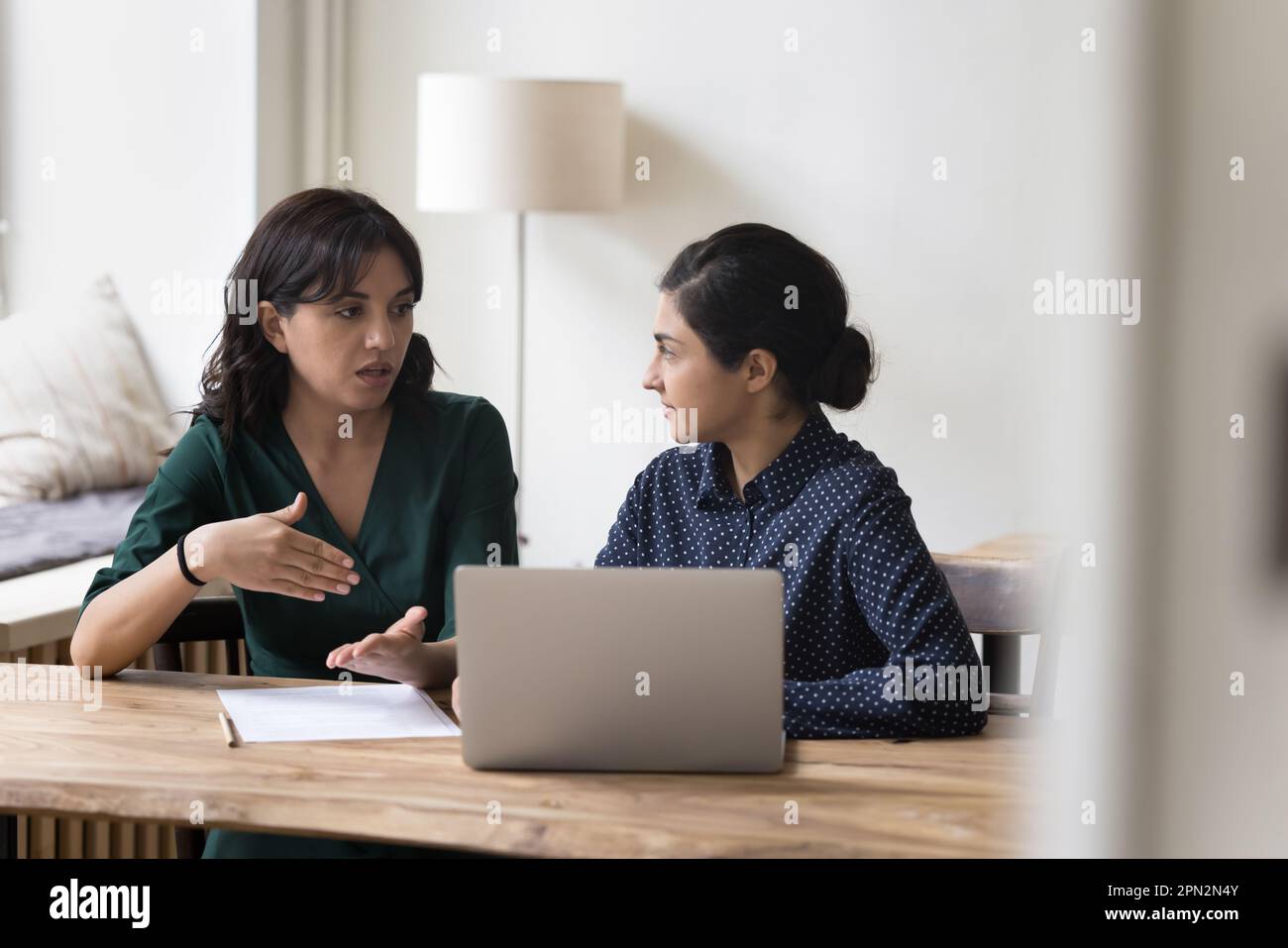 Multiethnische weibliche Kollegen sitzen am Schreibtisch, diskutieren über Projekte, teilen ihre Vision Stockfoto