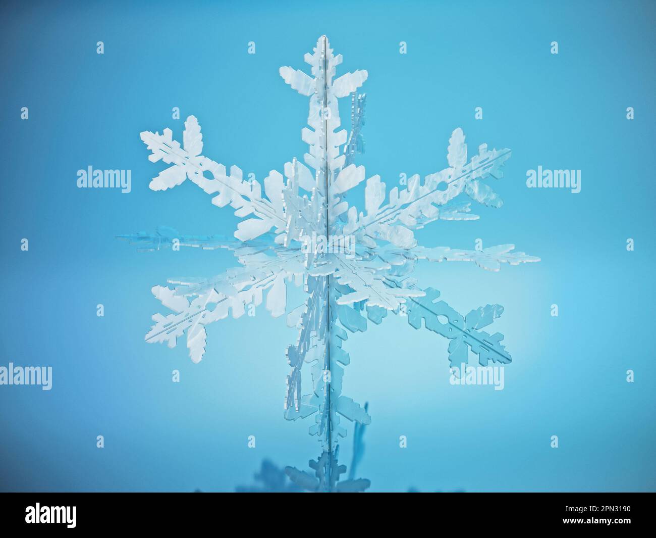 Schneeflocke steht auf blauer reflektierender Oberfläche. 3D Abbildung. Stockfoto
