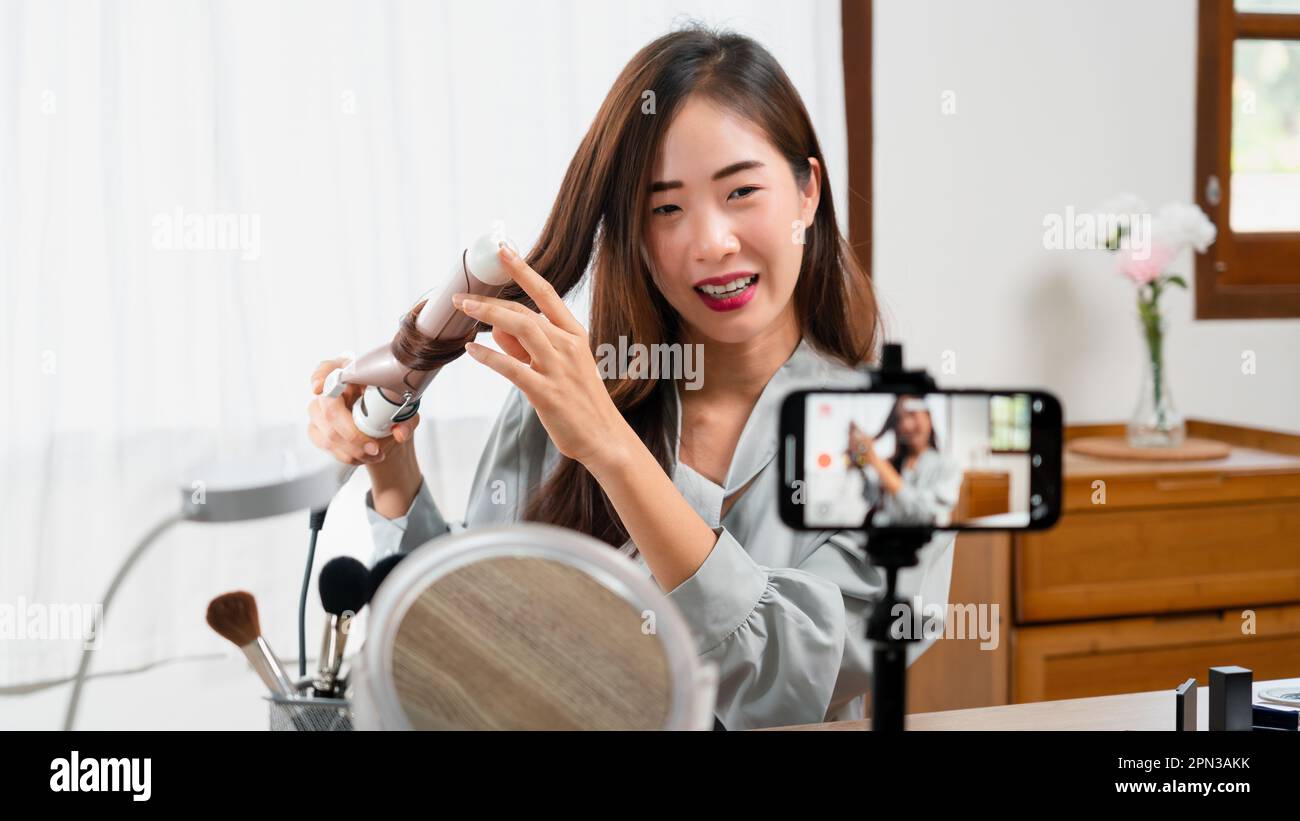 Beauty-Blogger Lockenstab mit Lockenstab und Videoaufnahme auf Smartphone für Make-up-Vlogger. Stockfoto