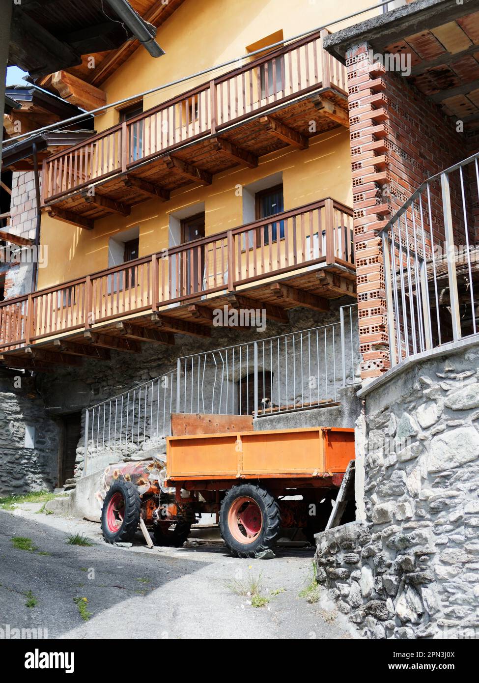 Orange gerendertes Gebäude mit orangefarbenem Anhänger in der Nähe von NUS im Aosta Valley, Italien. Die Gebäudestruktur besteht aus Stein und Ziegeln, wie in exponierten Bereichen zu sehen ist. Stockfoto