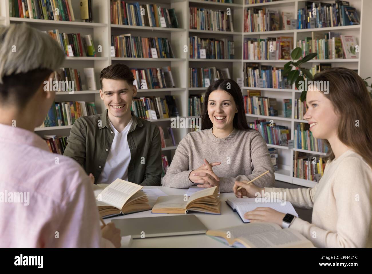 Vier Schüler erzählen Geschichten, die vom Lernen in der Bibliothek abgelenkt sind Stockfoto