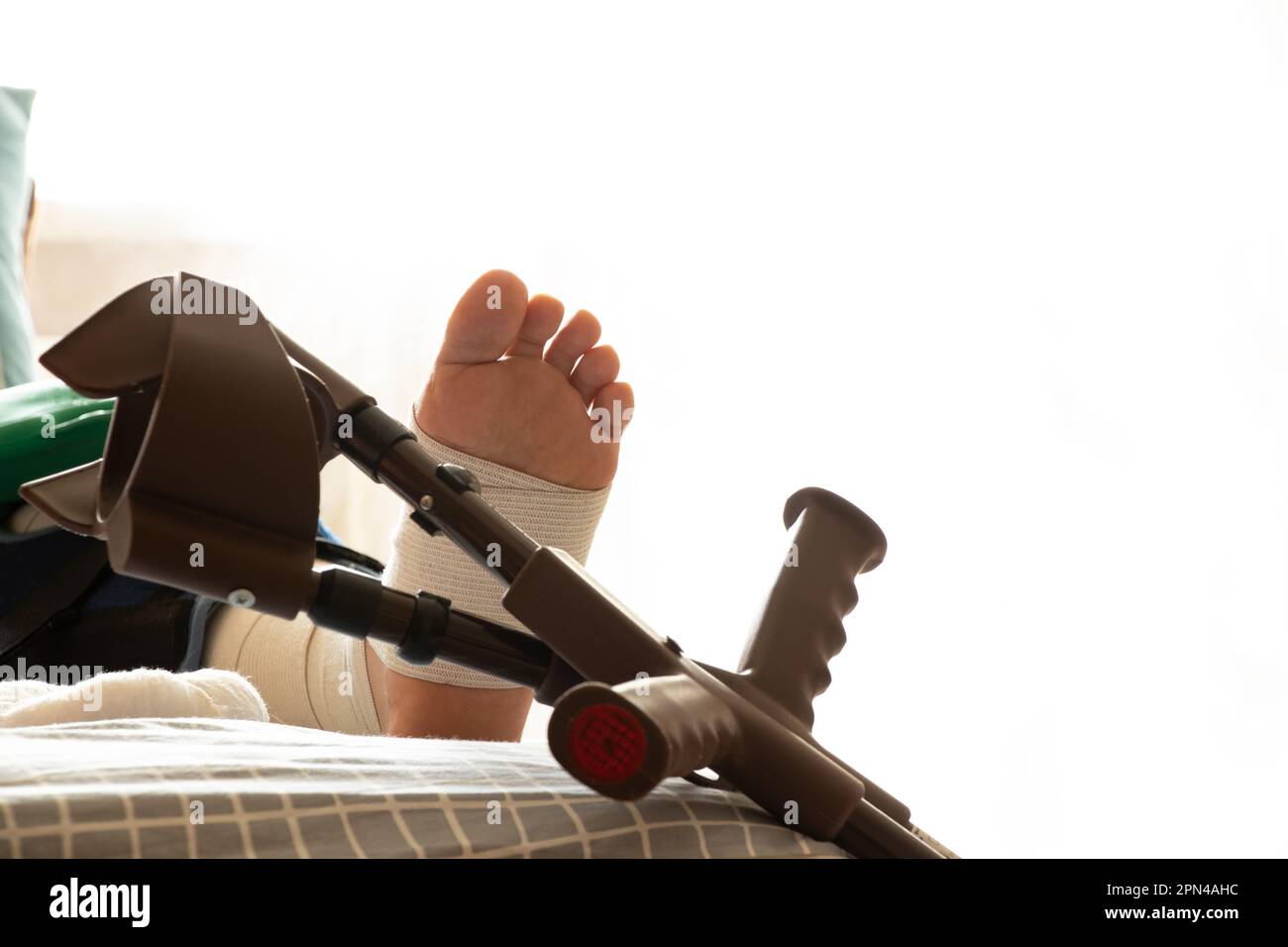 Ein Mann liegt nach einer Operation auf den Knien und Krücken neben dem Bett in der Wohnung, Rehabilitation nach der Operation, Beine Stockfoto