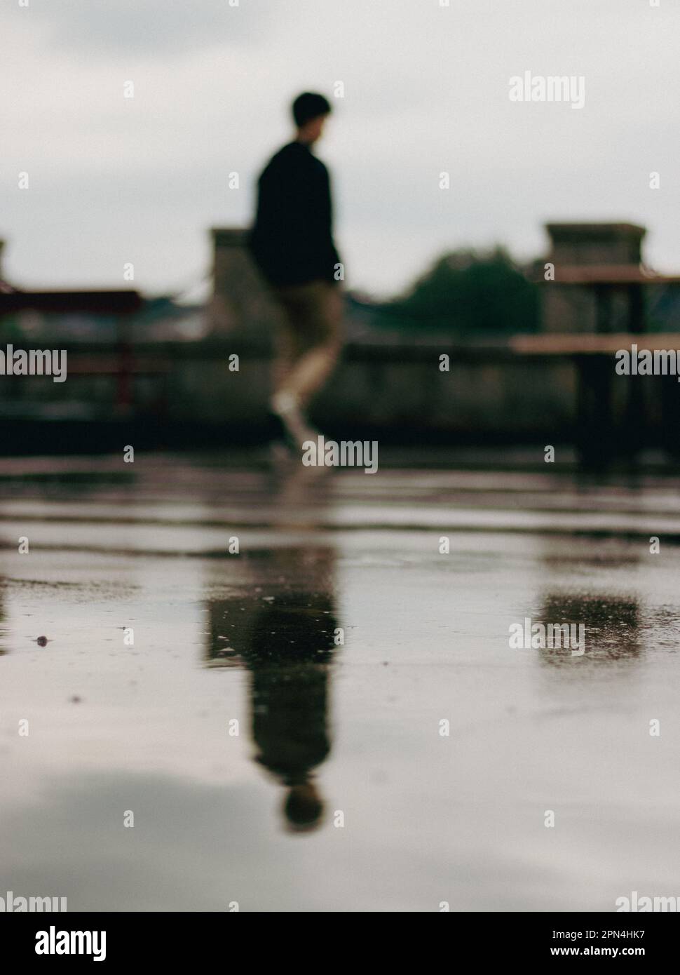 Die Silhouette eines Jungen spiegelt sich auf dem nassen Boden wider. Stockfoto