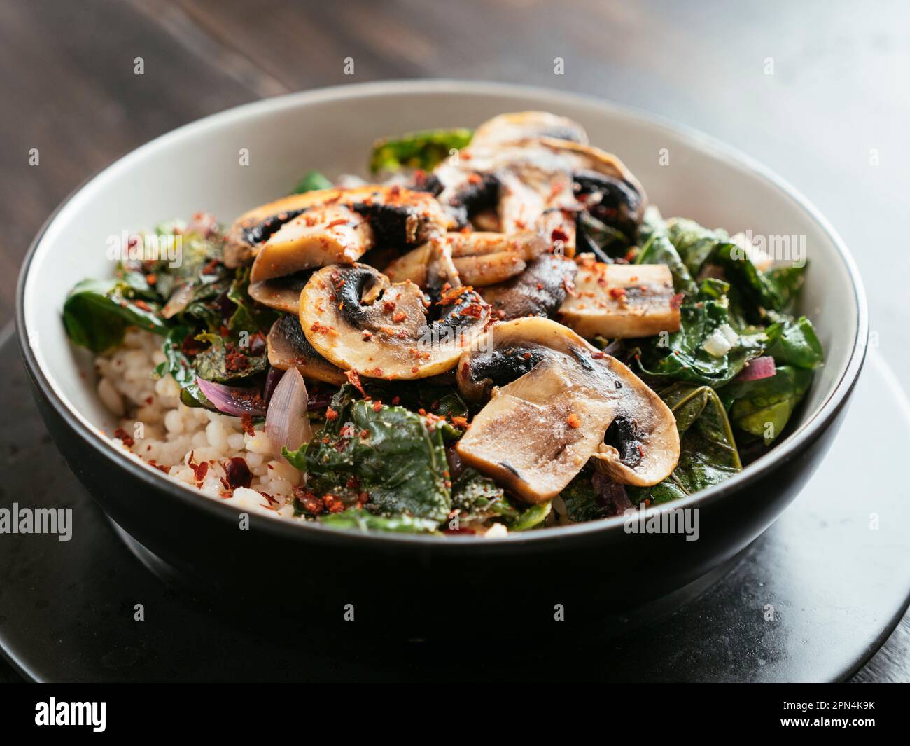 Senfgrün auf Gerste mit sautierten Pilzen Stockfoto