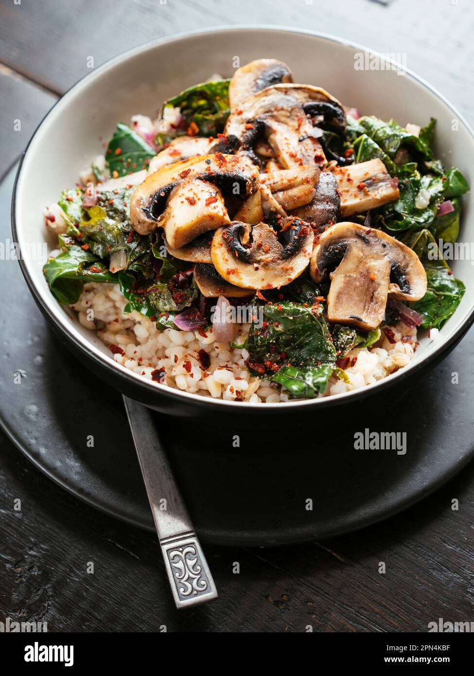 Senfgrün auf Gerste mit sautierten Pilzen Stockfoto