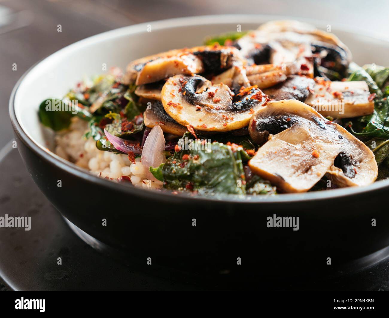 Senfgrün auf Gerste mit sautierten Pilzen Stockfoto