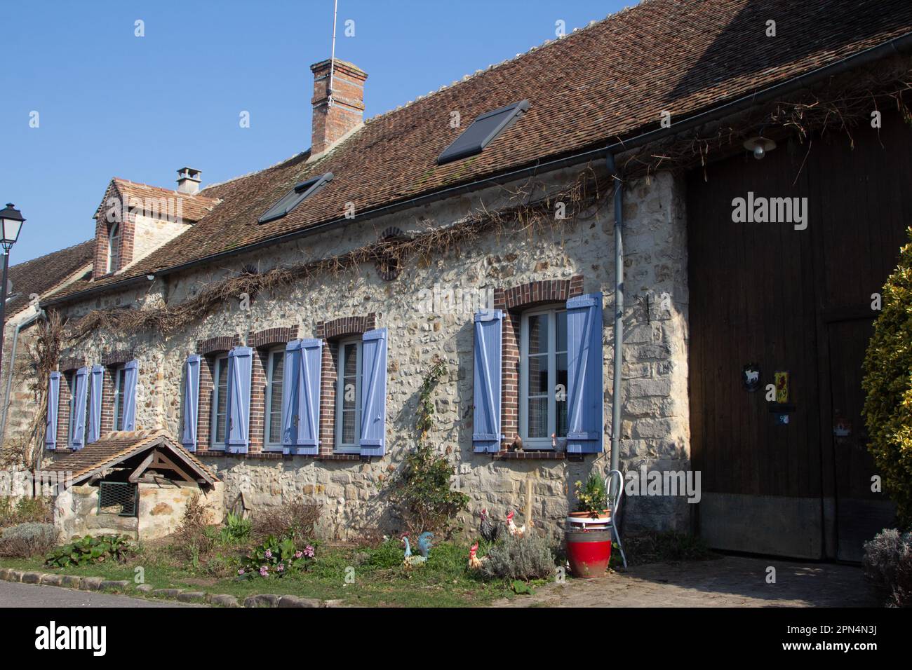 Flagy, Frankreich, hat 7 öffentliche Brunnen, die von Ludwig VII. Gebaut wurden Dieser schmückt einen Garten vor einem einstöckigen Steinhaus. Stockfoto