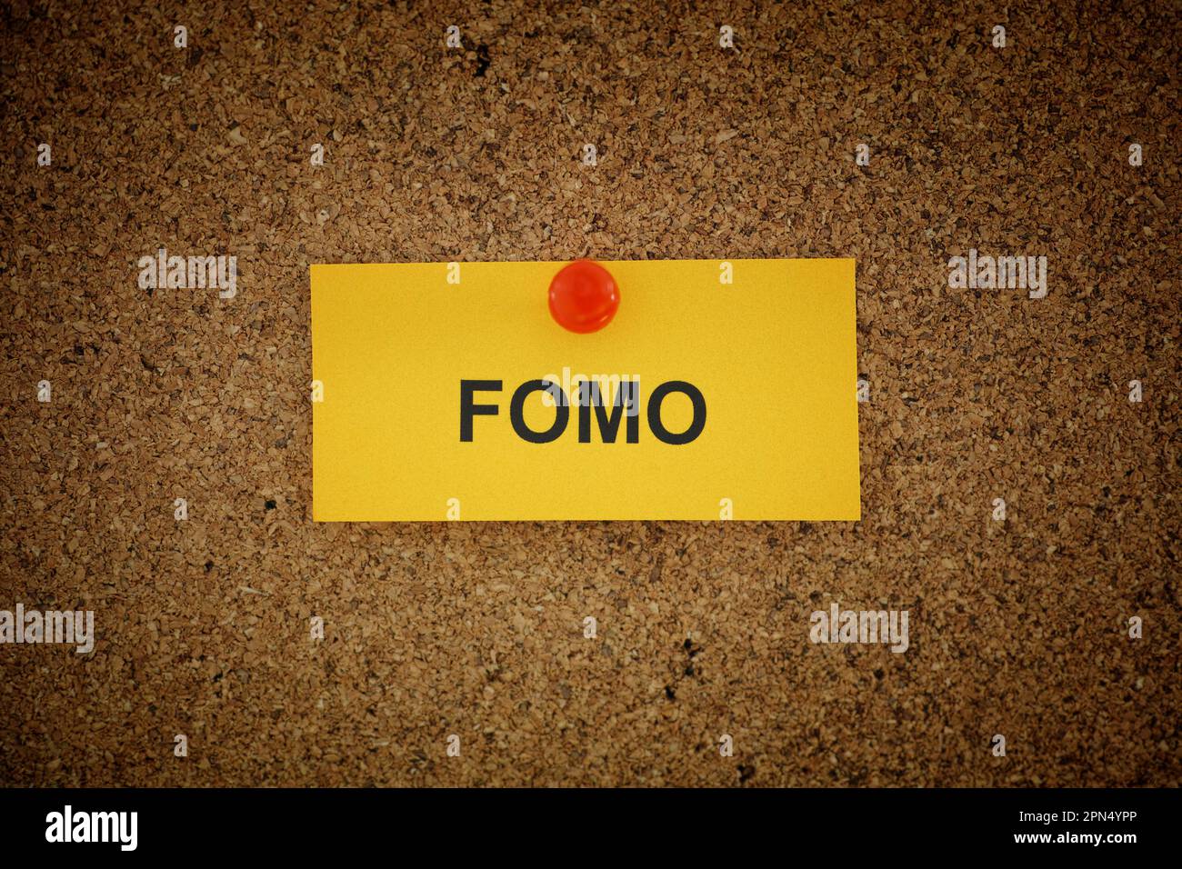 Ein gelber Zettel mit der Abkürzung FOMO (Fear of Missing Out) auf Korkbrett. Schließen. Stockfoto
