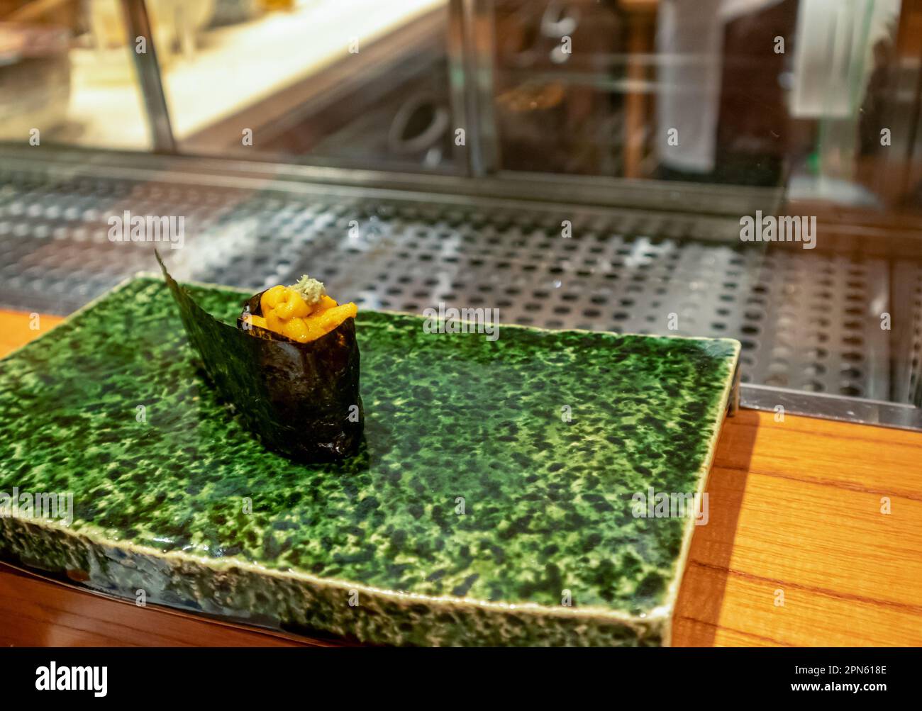 Heiße Sushi-Rolle isoliert auf einer grünen Keramikplatte Stockfoto