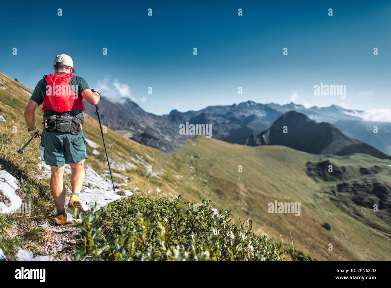 Ein Mann mittleren Alters, der auf einem Ausdauerpfad in den Bergen unterwegs ist Stockfoto