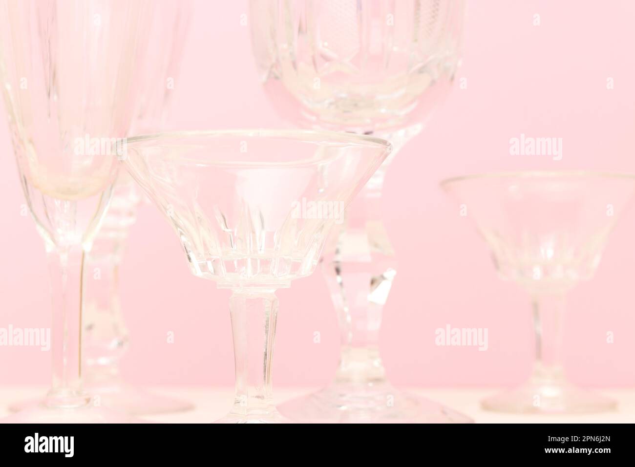 Nahaufnahme von klassischen Kristallgläsern vor pinkfarbenem Hintergrund. Stockfoto