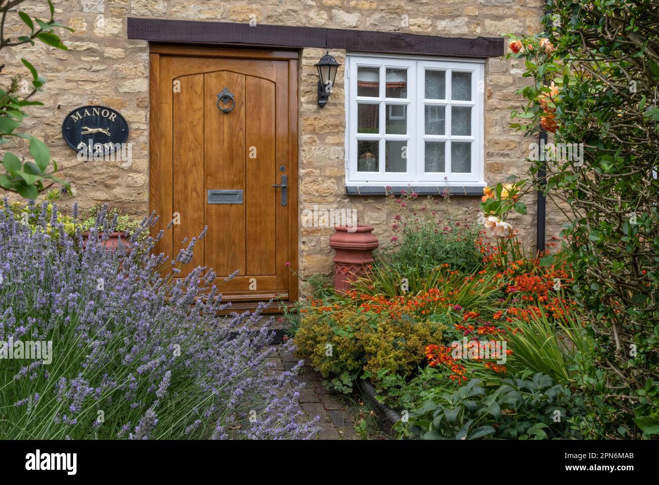 Garten im Cottage-Stil im Sommer vollgepackt mit Sträuchern und Blumen, Manor Farm, Stoke Bruerne, Northamptonshire, Großbritannien Stockfoto