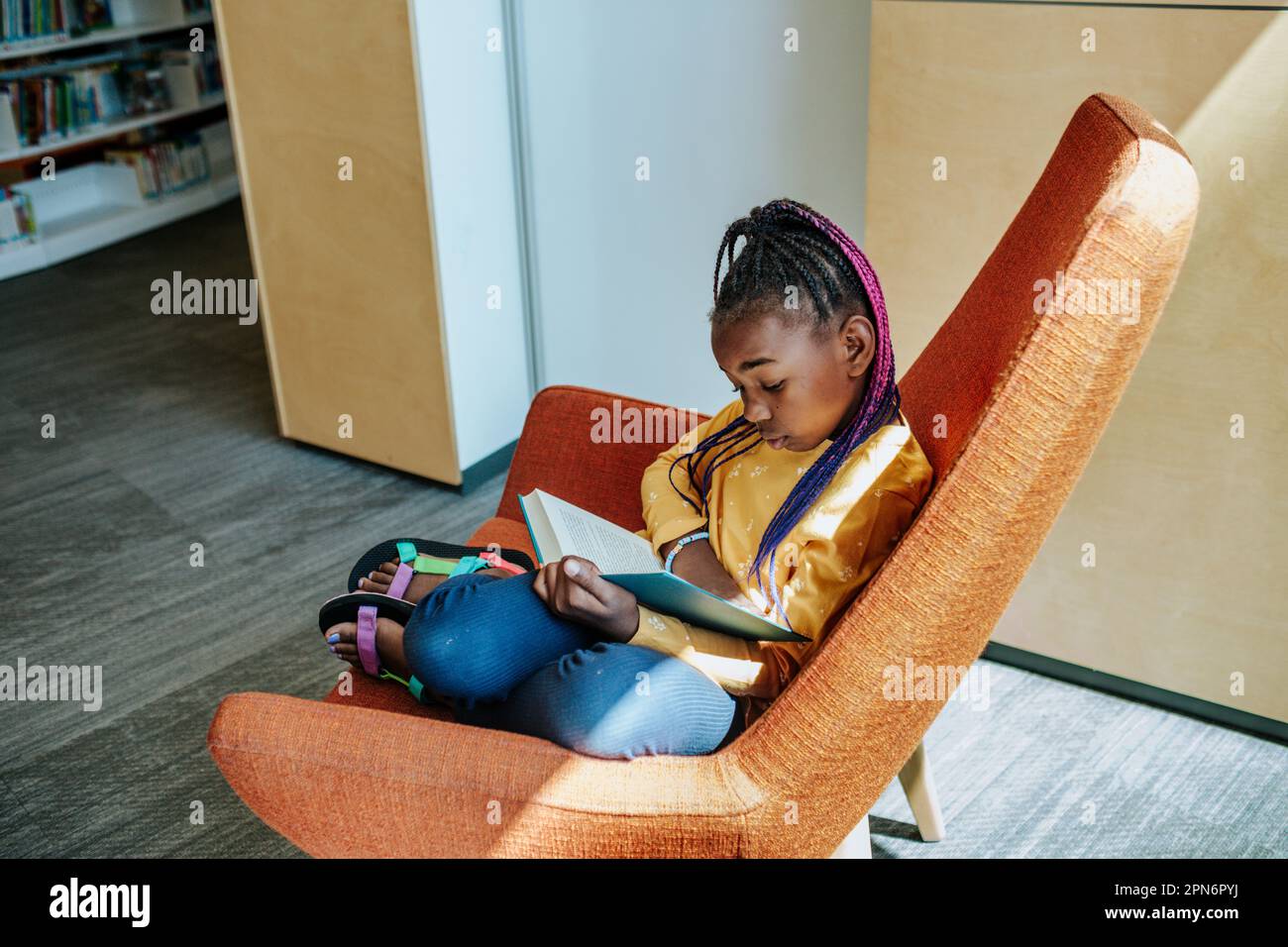 Ein junges Mädchen liest allein in einer ruhigen Ecke Stockfoto