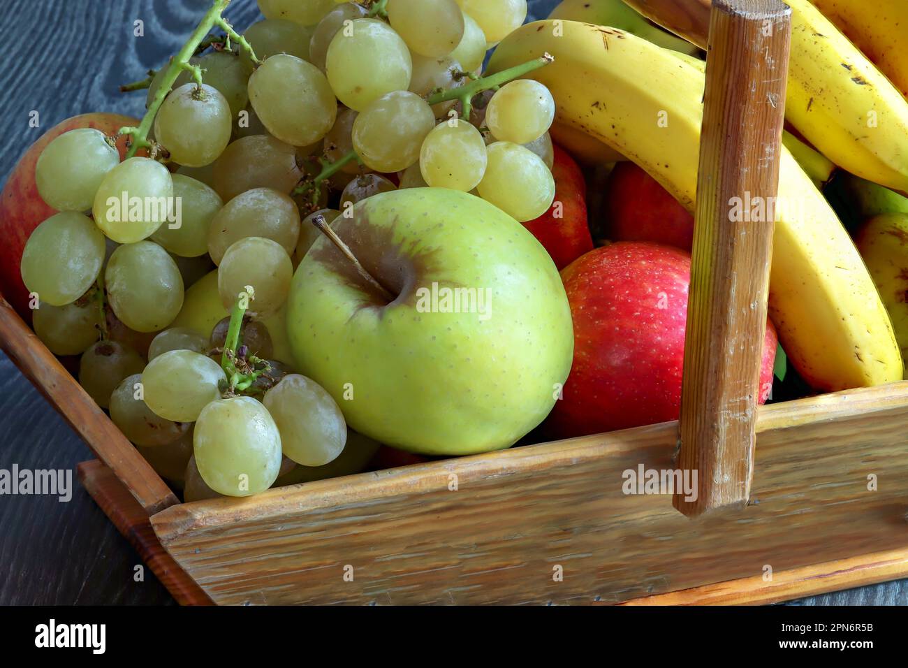 Trauben, Goldener Apfel, Bicolor und Banane in einem Erntekorb Stockfoto