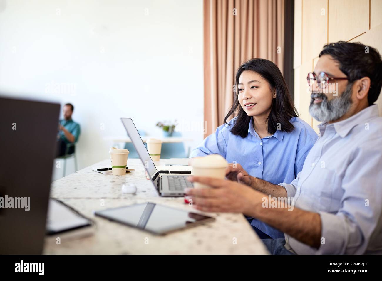 Geschäftsfrau, die ihren Laptop mit einem Kollegen im Café teilt Stockfoto