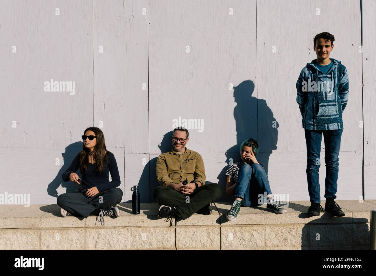 Vater und drei Teenager genießen Sunshine on A Wall Stockfoto