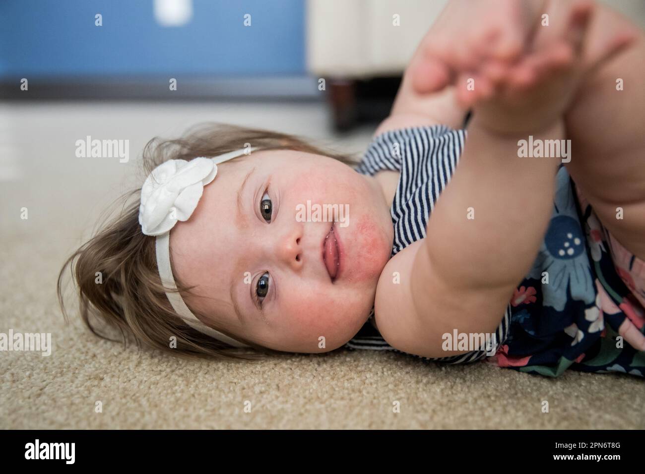Baby mit Down-Syndrom spielt auf dem Boden Stockfoto