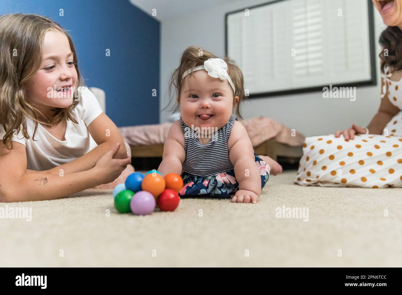 Glückliches Baby mit Down-Syndrom, das drinnen spielt Stockfoto