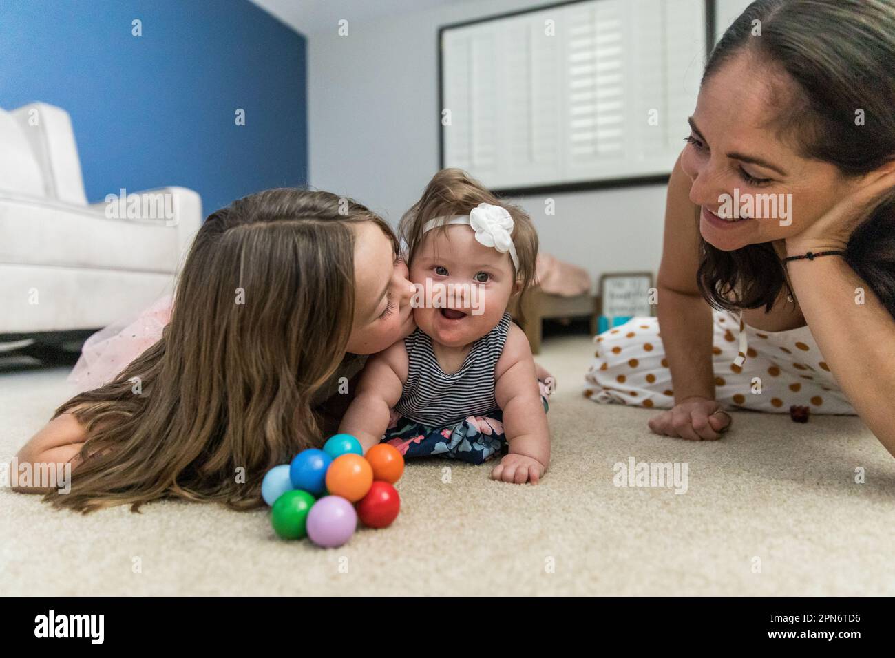 Die große Schwester spielt mit der Schwester für besondere Bedürfnisse auf dem Boden Stockfoto