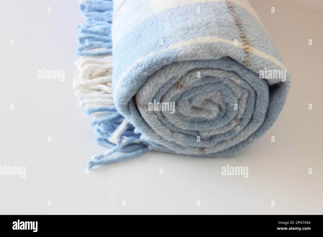 Karierte Wolldecke isoliert auf weißem Hintergrund. Weiß-blaue gerollte Decke. Stockfoto