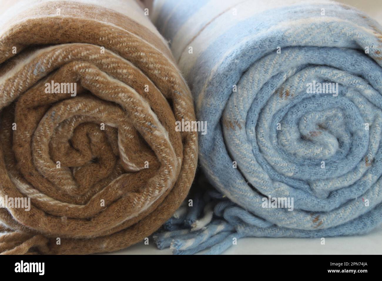 Karierte Wolldecke isoliert auf weißem Hintergrund. Beige-braune und weiß-blaue gerollte Decke. Schließen. Stockfoto