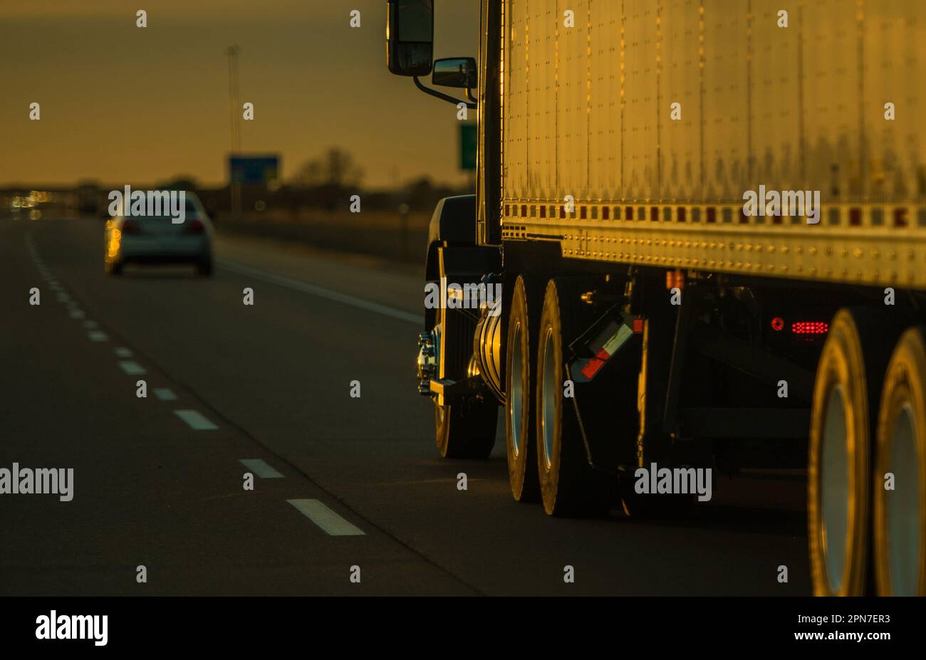 American Heavy Duty Semi Truck on the Road beleuchtet mit Sunset Light. Verschwommener Hintergrund mit Kopierbereich auf der linken Seite. Transportkonzept. Stockfoto