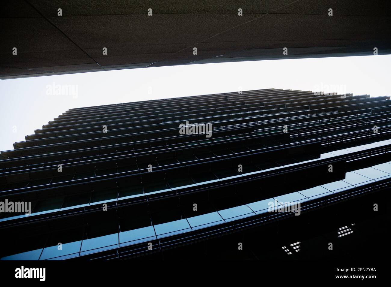 Blick aus einem niedrigen Winkel auf hohe Bürogebäude mit wunderschönem geometrischen Muster aus Licht und Schatten. Allgemeiner Architekturhintergrund mit dunklem Himmel Stockfoto
