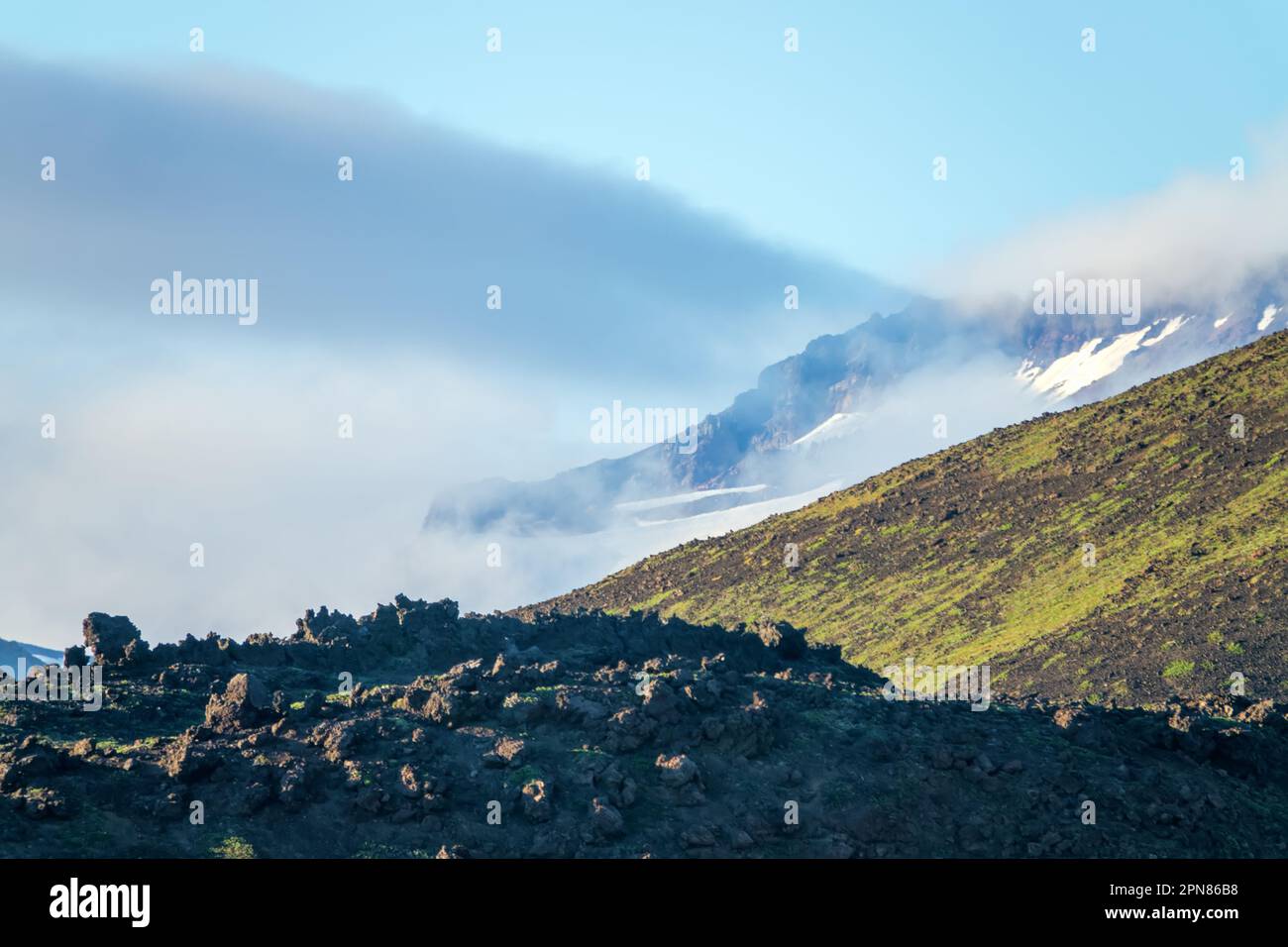 Die Wolken Rollen ins Tal. Panorama vulkanogener Berge. Lava und Pyroclast im Vordergrund Stockfoto
