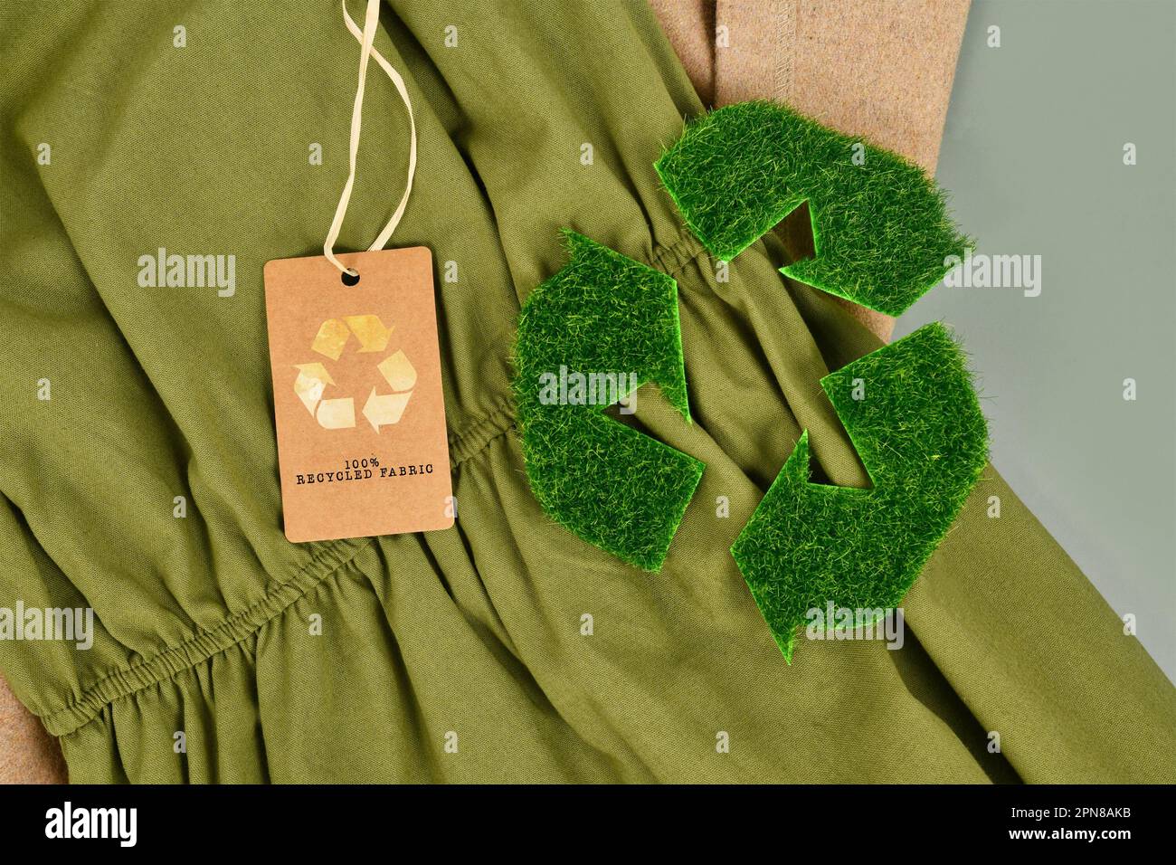 Umweltfreundliches Baumwollgewebe in Grün und Beige mit 100 % recyceltem Etikett und Recycling-Symbol aus Gras Stockfoto