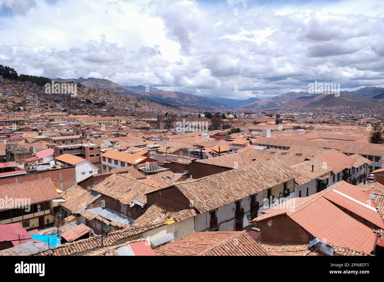 Blick von oben auf die historischen Häuser und das Dach von Cusco mit der Kathedrale von Cusco, den Anden und dem bewölkten Himmel im Hintergrund. Cusco betrachten den Hintergrund des Reisekonzepts. Stockfoto