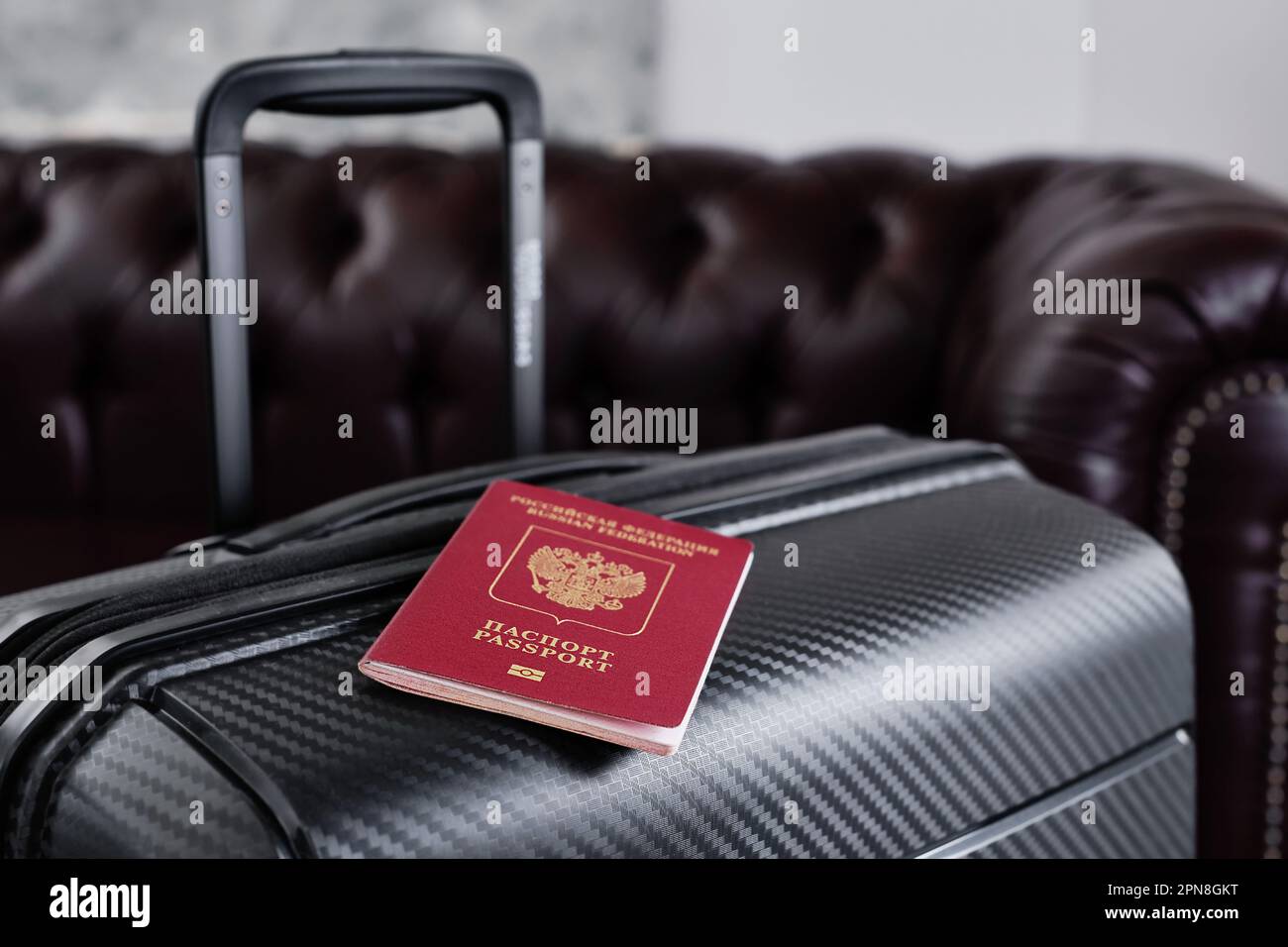 Russischer Pass auf schwarzem Reisekoffer, selektiver Fokus. Auswanderung von Russen aus dem Land, Visaprobleme, Flüchtlinge Stockfoto