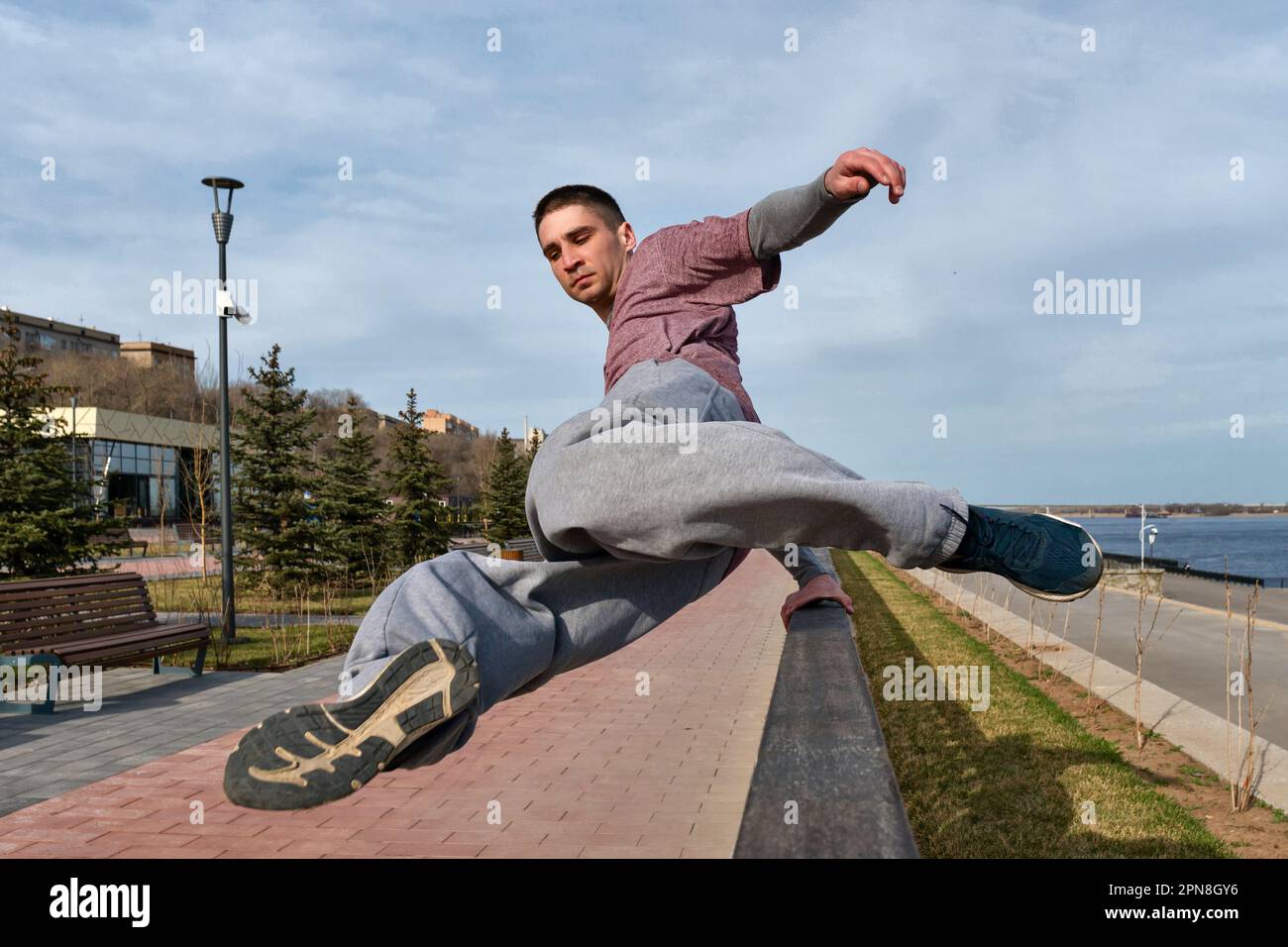 Sportler, der Parkour im städtischen Raum praktiziert. Parkour-Sportler, der über das Geländer springt. Aktiver Lifestyle. Akrobatik im Freien Stockfoto