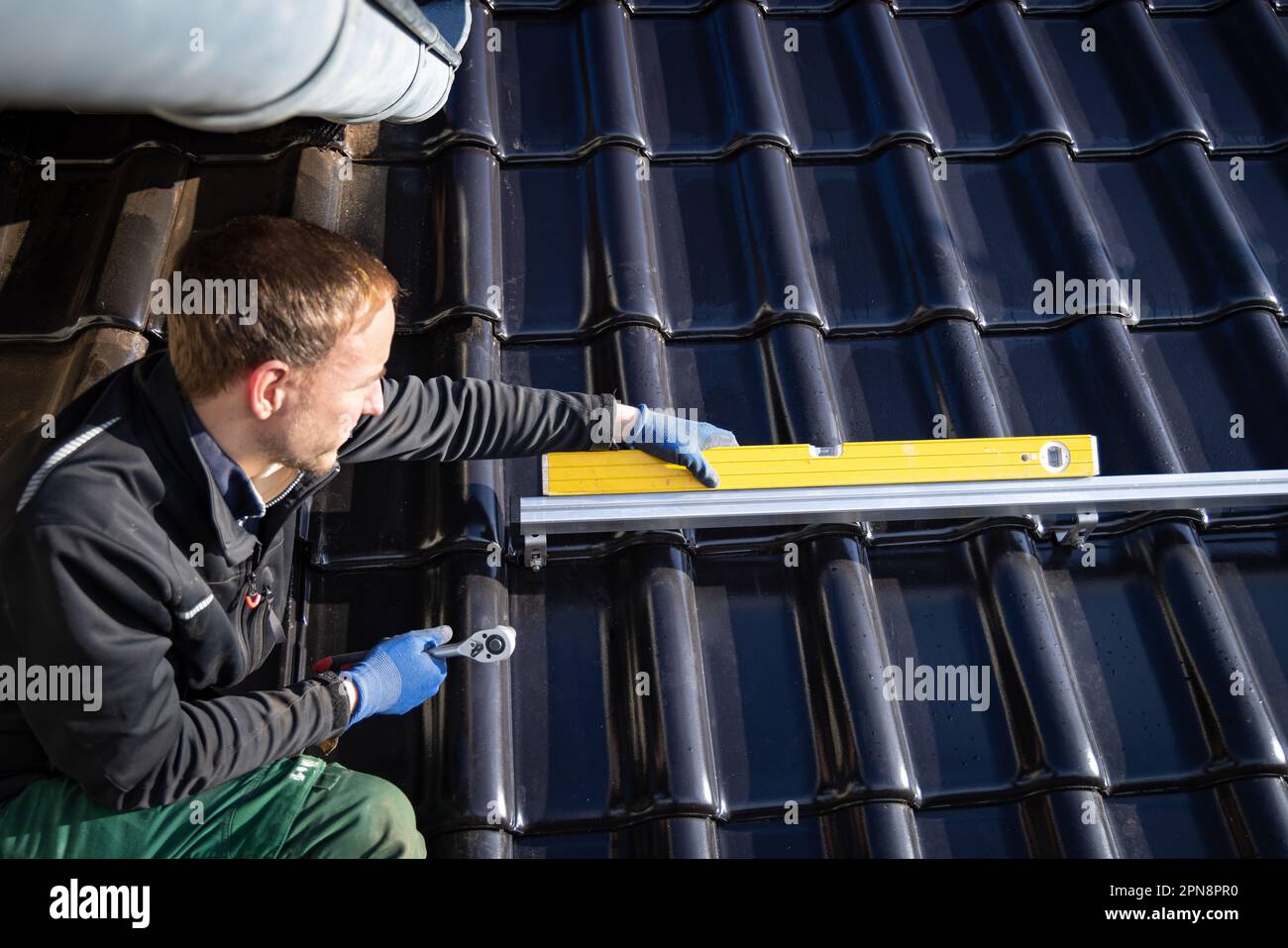 Handwerker, der eine Wasserwaage auf einer Montageschiene für Solarmodule verwendet Stockfoto
