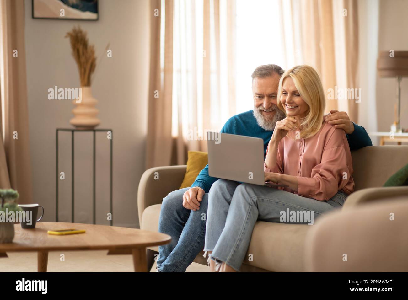 Fröhliches, Reifes Paar, Das Den Laptop Zu Hause Auf Dem Sofa Benutzt Stockfoto