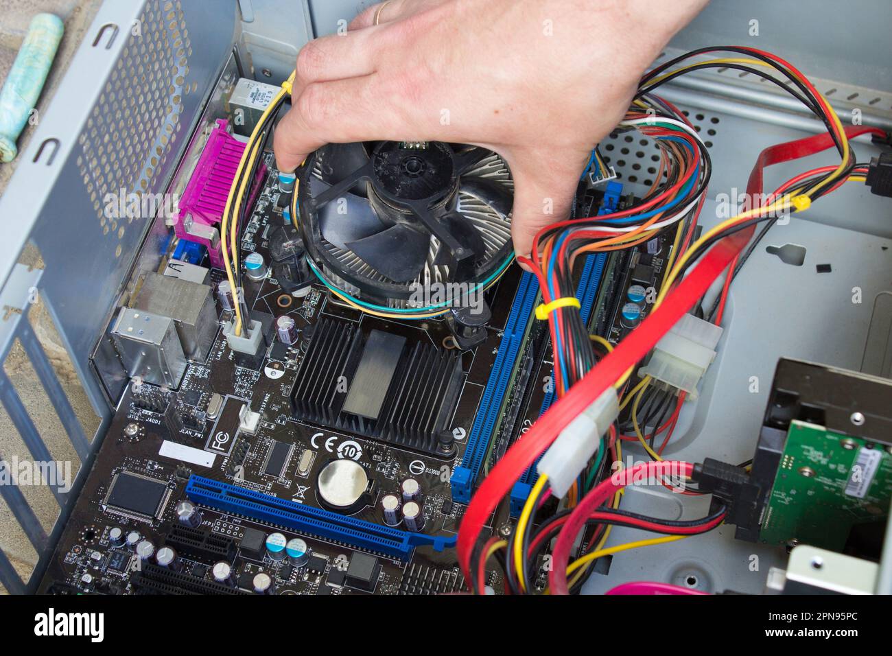 Die Person repariert die Hauptplatine des Computers und zerlegt den Prozessor Stockfoto
