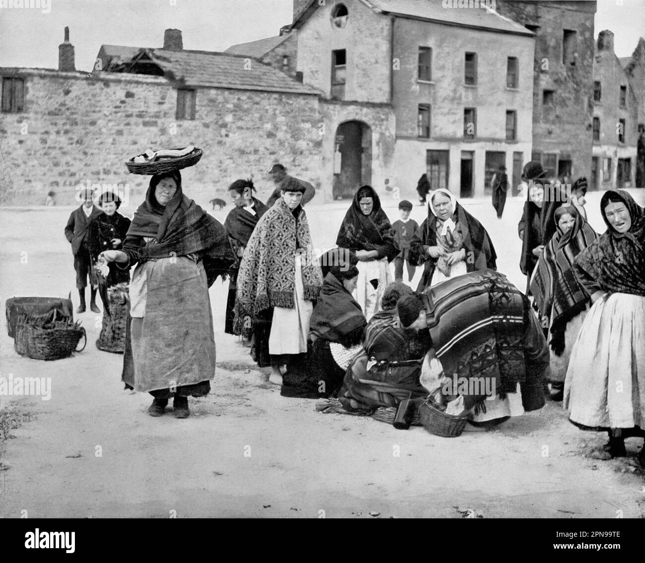 Ein Blick aus dem späten 19. Jahrhundert auf den Fischmarkt in der Nähe eines der alten Stadttore in Galway City, Irland. Die älteren Frauen und ein oder zwei jüngere Mädchen sind Claddagh-Leute, die den neu gefangenen Hering verkaufen, für den die Küste von Galway berühmt ist. Stockfoto