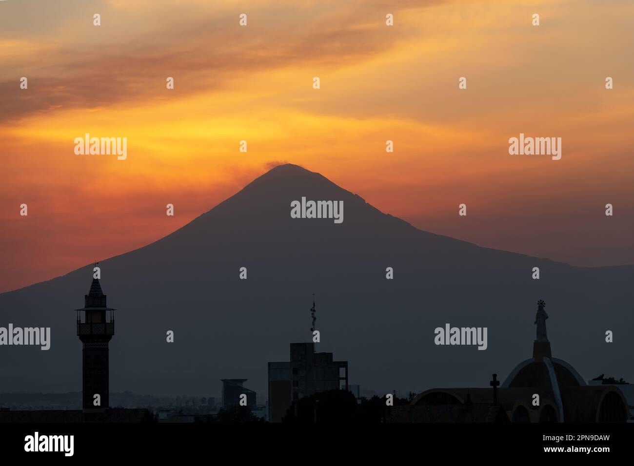 Silhouette des Vulkans Popocatepetl bei Sonnenaufgang mit vulkanischer Aktivität und Puebla Stadtbild, Puebla State, Mexiko. Stockfoto